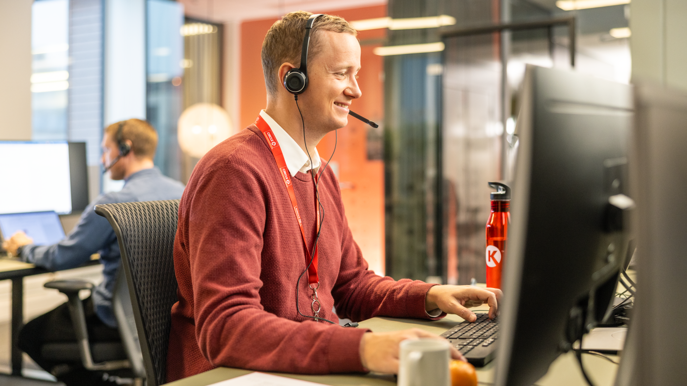Circle K employee sitting at his desk with a headset on, supporting customers on a call
