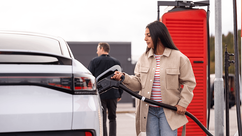 Femme utilisant une borne de recharge pour charger sa voiture électrique